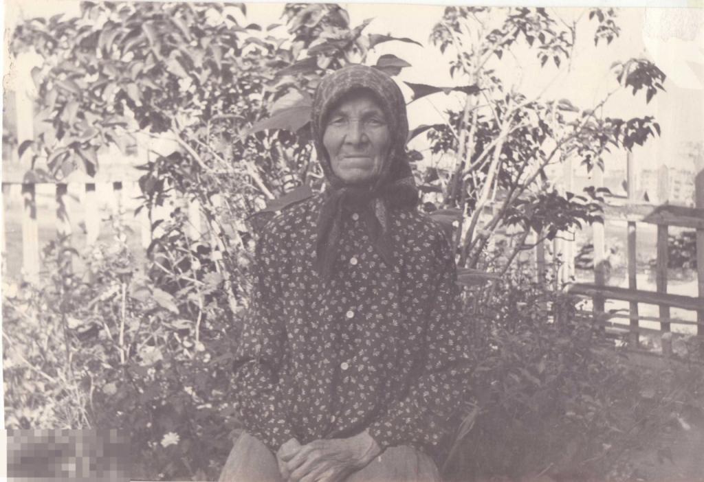 Бабушка в платочке сидит в саду. 1970-е гг.