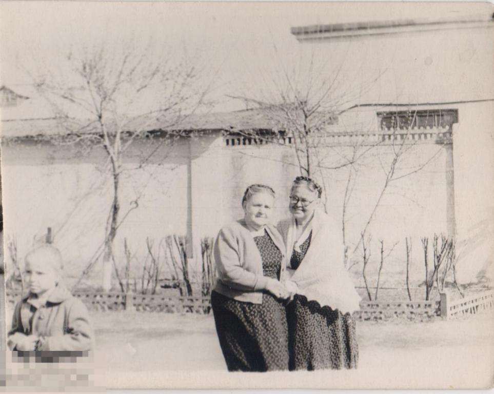 Две бабушки и одна маленькая девочка у стены с палисадником. 1960-е гг.