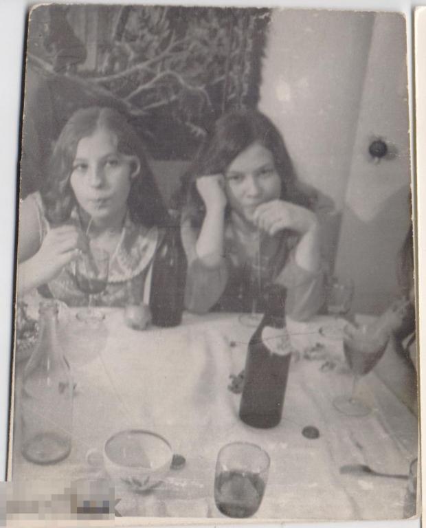 Две девушки с соломинками сидят за праздничным столом. 1975 г.