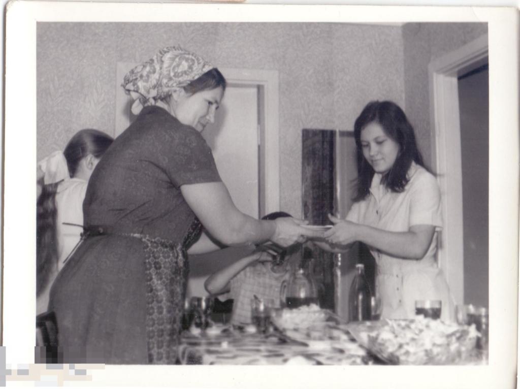 Женщина передает девушке тарелку на дне рождения Женьки. 1975 г.