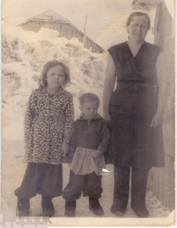 Женщина с двумя маленькими девочками зимой у стены дома. 1950-60-е гг.