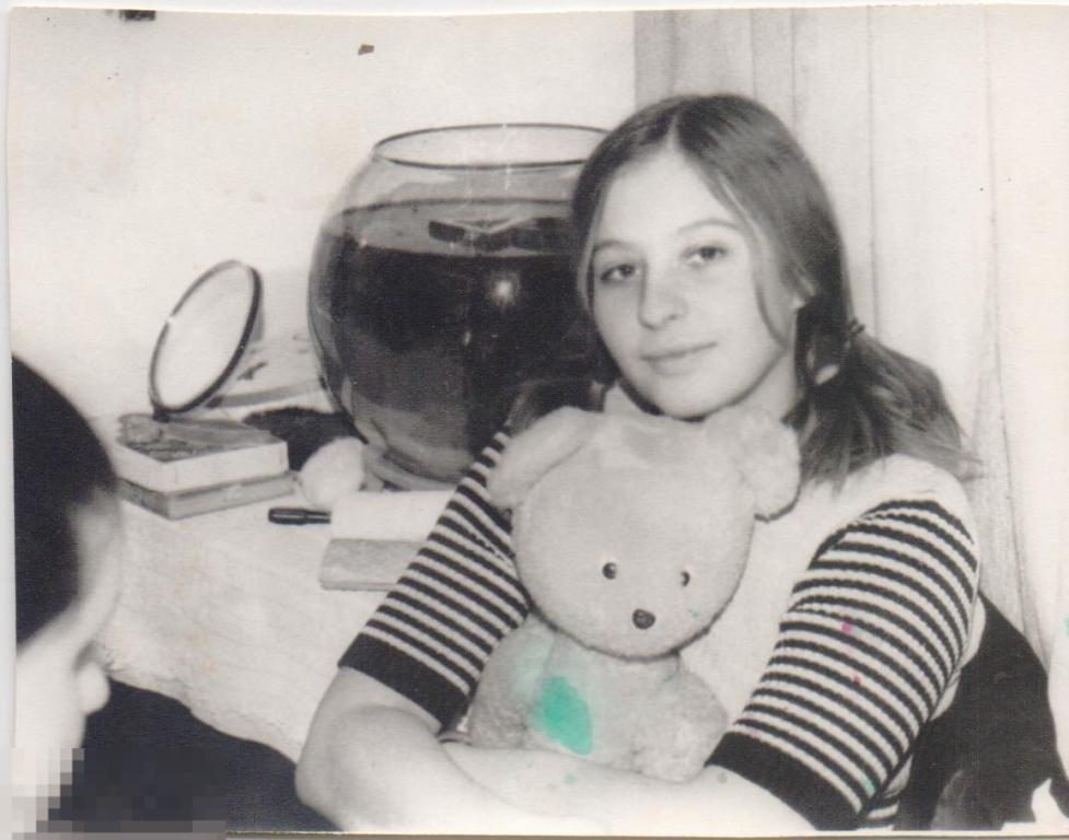 Девушка сидит с плюшевым мишкой у аквариума. 1975 г.
