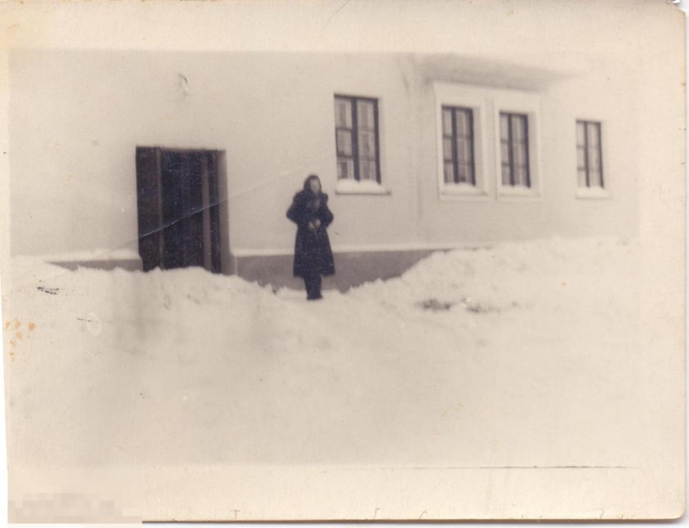 Девушка стоит зимой у дверей подъезда дома. 1950-60-е гг.