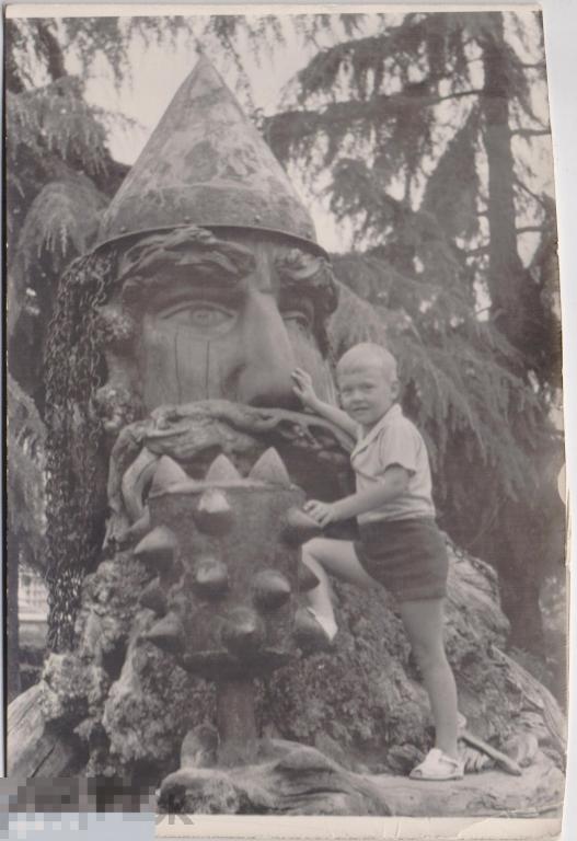 Маленький мальчик в шортах у деревянной скульптуры богатыря. 1960-е гг.