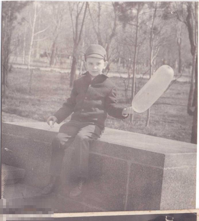 Маленький мальчик сидит на парапете с воздушным шариком. 1960-е гг.