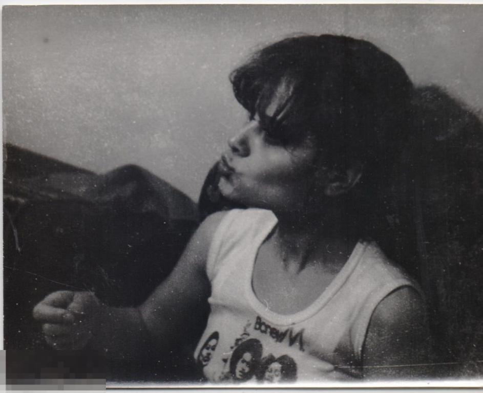 Девушка в майке Boney M сидит на диване. 1970-80-е гг.