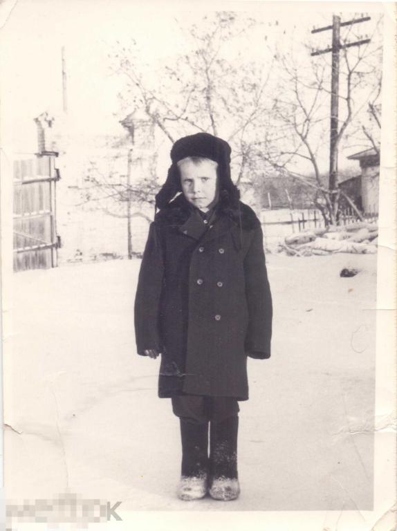 Маленький мальчик в зимней одежде стоит на улице. 1960-е гг.
