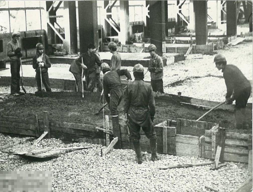 Группа молодых рабочих цементирует пол цеха. 1970-е гг.