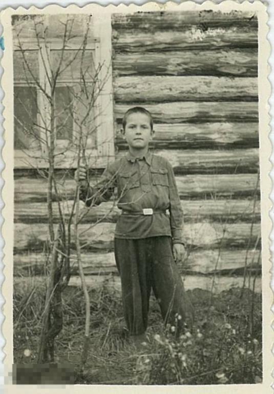 Мальчик в гимнастерке на фоне деревянной стены дома. 1950-е гг.
